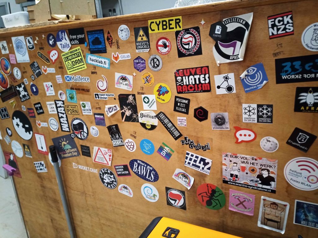 Picture of the wooden 'bar' covered in various technology and hacker related stickers.